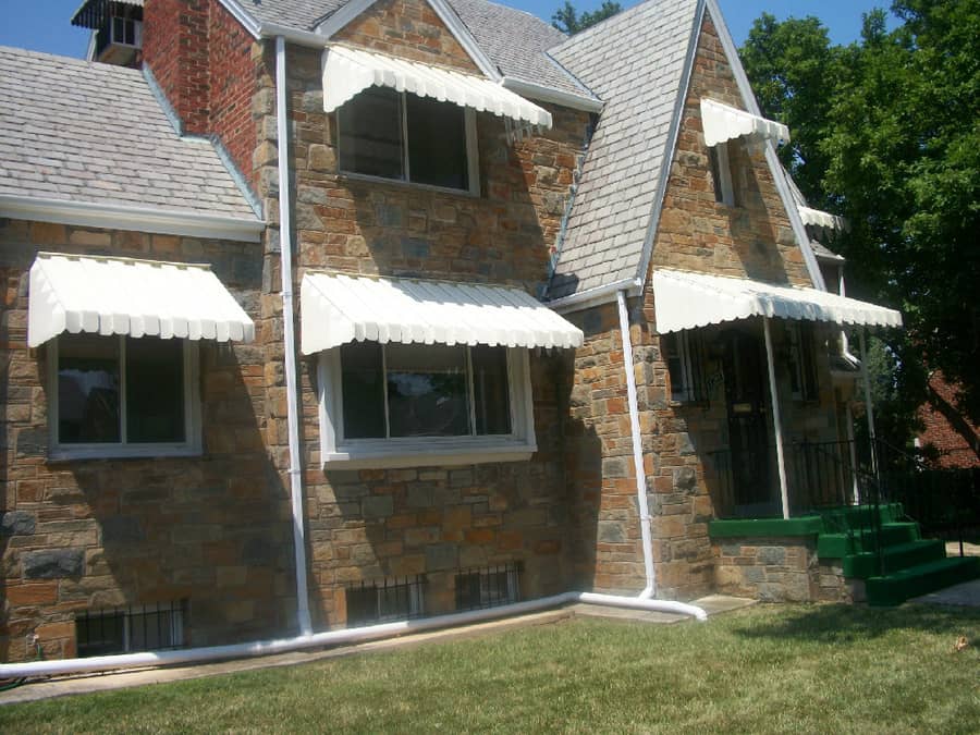 A brick house with white awnings on the front.