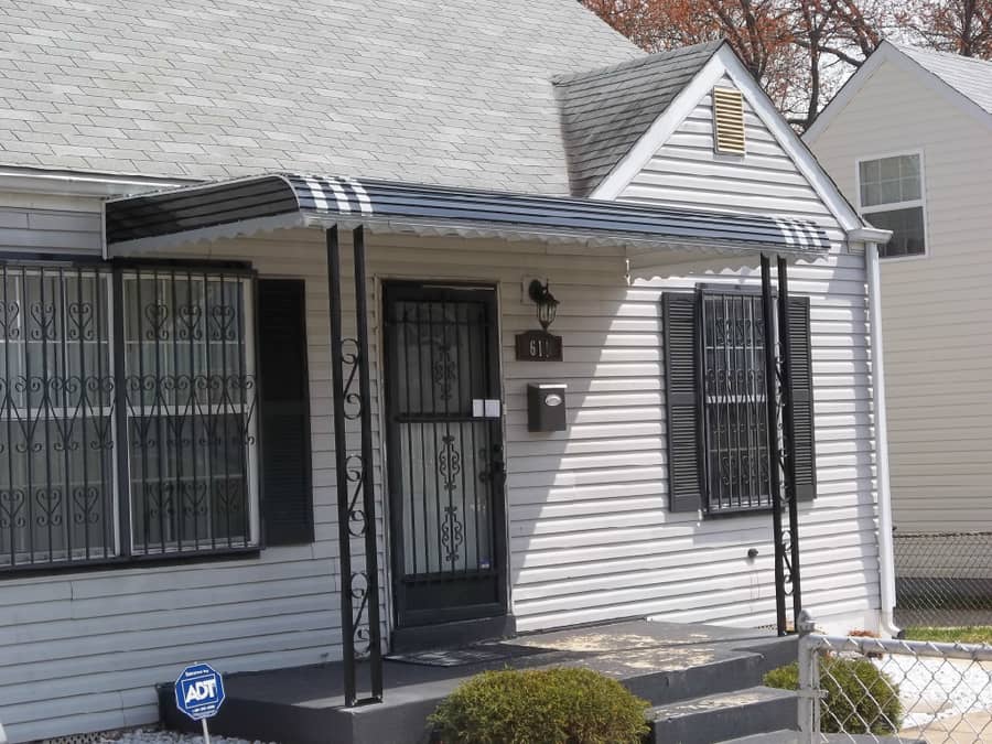 A house with a black and white awning on the front of it.