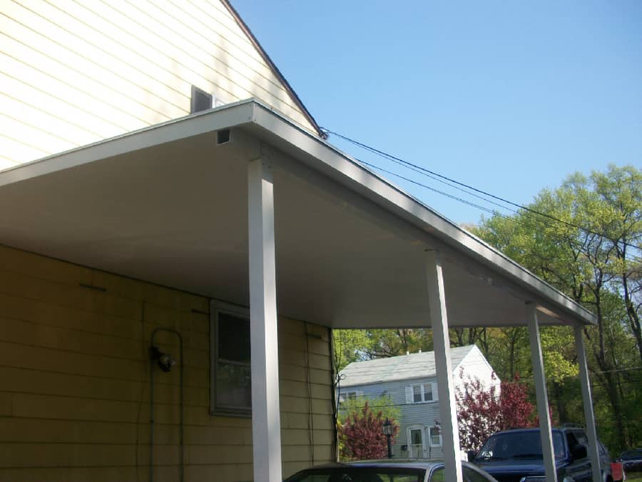 A car parked in front of a house with a white roof.