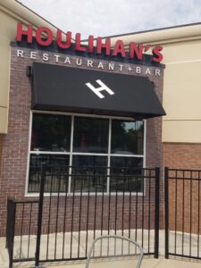 A restaurant with a black awning and red lettering.